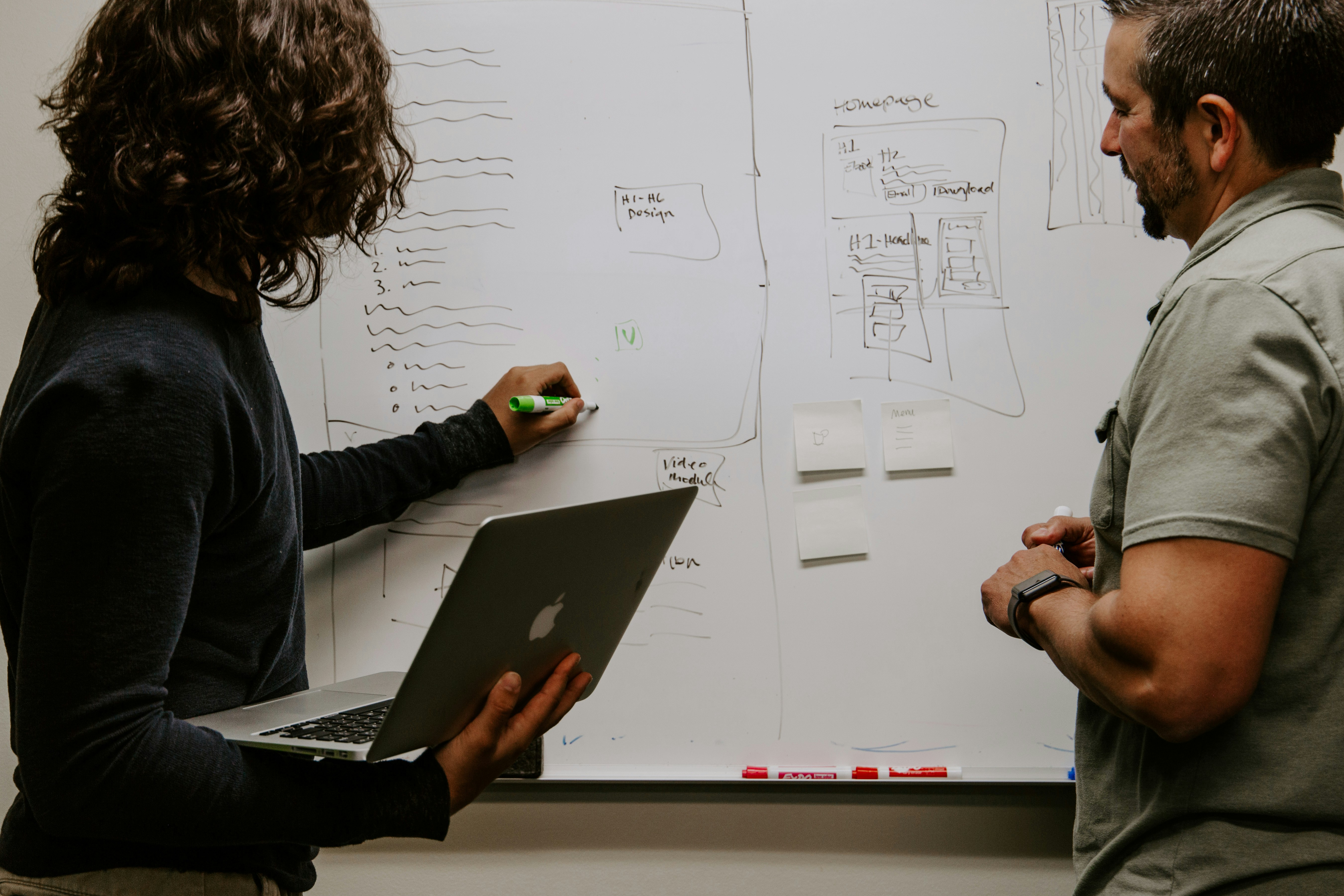 two engineers at a whiteboard with a laptop